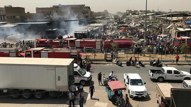 People and security forces gather at the scene of a car bomb explosion in the wholesale Jamila market in Baghdad,Iraq. Security sources said the bombing occurred near one of Baghdad’s largest shopping centres at around 10:30 am. (Ali Abdul Hassan / AP)
