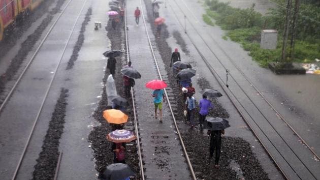 People walk on water-logged railway tracks in Mumbai on Tuesday.(REUTERS)