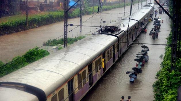 Commuters walk through rain waters along a local train after heavy rains lashed Mumbai on Tuesday.(PTI Photo)