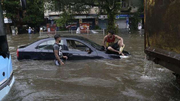 A man sits on a car that got stuck in a waterlogged street following heavy rains in Mumbai. (AP Photo) A man sits on a car that got stuck in a waterlogged street following heavy rains in Mumbai. (AP Photo)