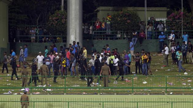 Sri Lankan police personnel ask people to leave after some spectators threw plastic bottles in the ground to disrupt play during the third One-Day International (ODI) between Sri Lanka and India in Pallekele on Sunday.(AP)