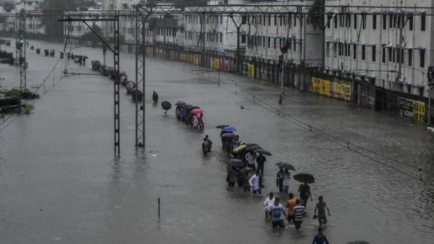 People walk on a submerged railway track at Matunga on Tuesday.(Kunal Patil/HT Photo)