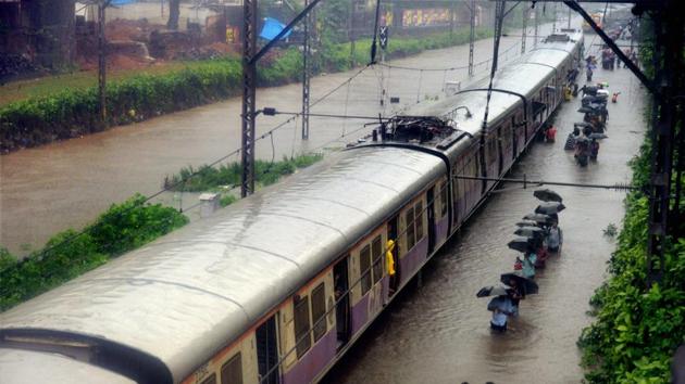 Commuters walk through rain waters along a local train after heavy rains lashed Mumbai on Tuesday. (PTI Photo) Commuters walk through rain waters along a local train after heavy rains lashed Mumbai on Tuesday. (PTI Photo)