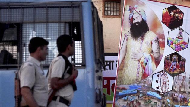 Policemen walk past a poster of Baba Ram Rahim while patrolling street in Sirsa after the Dera chief was sentenced to 20 years in jail in two rape cases against him. (PTI File) Policemen walk past a poster of Baba Ram Rahim while patrolling street in Sirsa after the Dera chief was sentenced to 20 years in jail in two rape cases against him. (PTI File)
