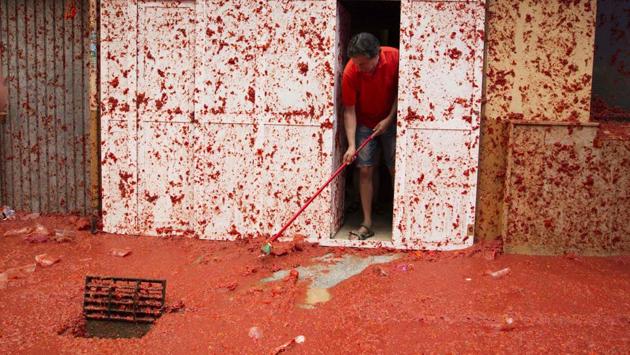The streets are then hosed down by fire trucks and participants often use hoses provided by the locals to remove the tomatoes from their bodies. (JAIME REINA / AFP)
