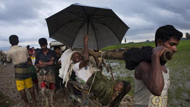 Rohingya carry an elderly man and walk through rice fields after crossing over to the Bangladesh side of the border near Cox's Bazar's Teknaf area on September 1.(AP File Photo)