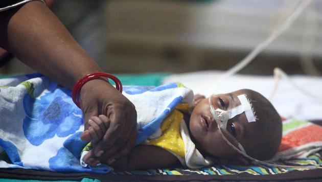 A woman holding her child's hand at the encephalitis ward of the Baba Raghav Das Hospital in Gorakhpur on August 14.(AFP File Photo) A woman holding her child's hand at the encephalitis ward of the Baba Raghav Das Hospital in Gorakhpur on August 14.(AFP File Photo)