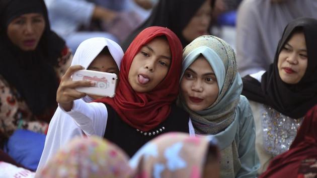 Girls take a selfie during a morning prayer marking Eid al-Adha holiday at Sunda Kelapa Port in Jakarta, Indonesia (Dita Alangkara / AP)
