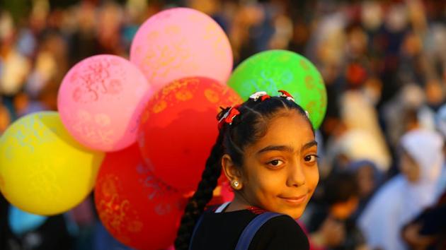 A Palestinian girl carries balloons while celebrating at the main square in Gaza City after performing the morning prayer for Eid al-Adha (Mohammed Abed / AFP)