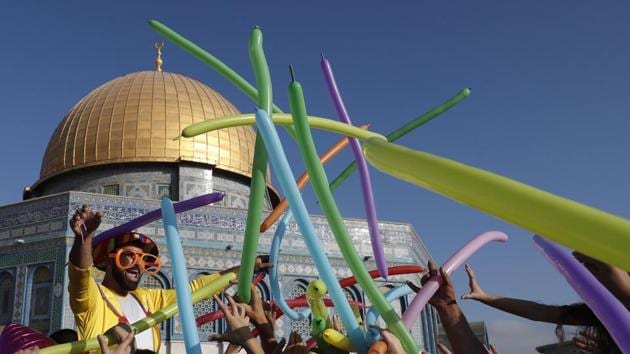A man dressed in a clown outfit distributes balloons to children by the Dome of the Rock inside al-Aqsa Mosque compound, in Jerusalem's old city on the first day of Eid al-Adha. (Ahmad Gharabli / AFP)
