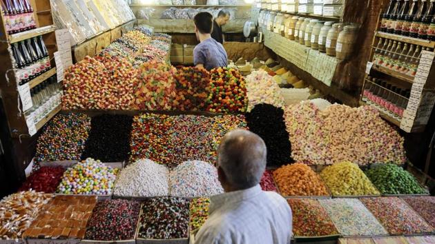 People buy sweets from a stall at al-Bazourieh popular market in the old part of the capital Damascus, in preparation for celebrations for Eid al-Adha. Syrian President Bashar Assad traveled Friday to a town recently captured from Islamic State group militants to attend Eid al-Adha prayers. (Louai Beshara / AFP)
