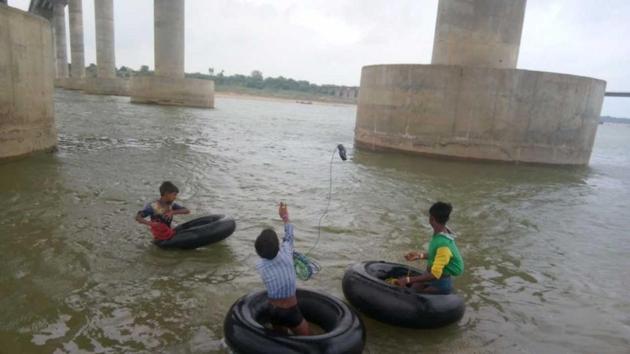 Boys enter river waters on truck tubes, connected with magnets in long ropes. (HT Photo) Boys enter river waters on truck tubes, connected with magnets in long ropes. (HT Photo)