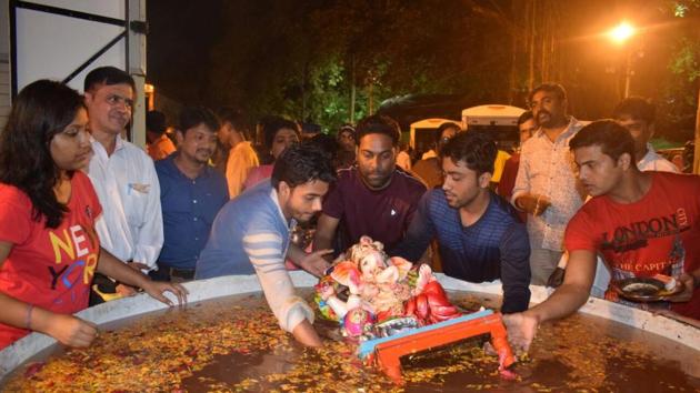People dip idols in the artificial pond built by the student group in Aarey Milk Colony in Mumbai.(HT)