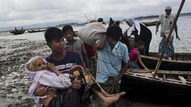 A Rohingya ethnic minority man from Myanmar carries an elderly woman as they alight from a local boat after crossing over to the Bangladesh side of the border near Cox's Bazar's Dakhinpara area on Saturday. (AP) A Rohingya ethnic minority man from Myanmar carries an elderly woman as they alight from a local boat after crossing over to the Bangladesh side of the border near Cox's Bazar's Dakhinpara area on Saturday. (AP)