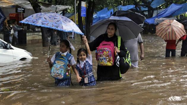 Schoolchildren walk through a waterlogged street in Mumbai. Unicef said almost 16 million children and their families are in urgent need of life-saving support.(AP)