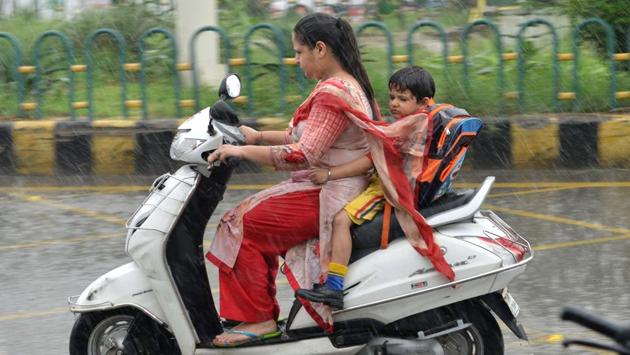 An Indian woman rides a bike with a boy during heavy rains in Amritsar. (NARINDER NANU / AFP) An Indian woman rides a bike with a boy during heavy rains in Amritsar. (NARINDER NANU / AFP)