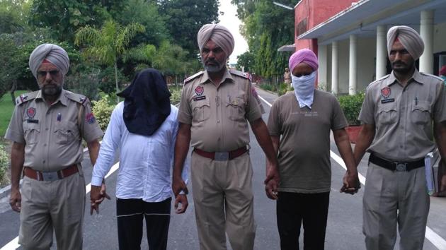 Dera followers Duni Chand and Ranjit Singh (with faces covered) in police custody in Sangrur on Monday.(HT Photo)