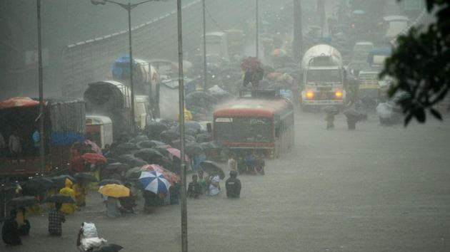 People wade along a flooded street during heavy rain showers in Mumbai on August 29, 2017(AFP)