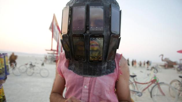 Derek Schoonmaker walks on the playa with his helmet made of android phones as an experimental project. (Jim Urquhart / REUTERS) 