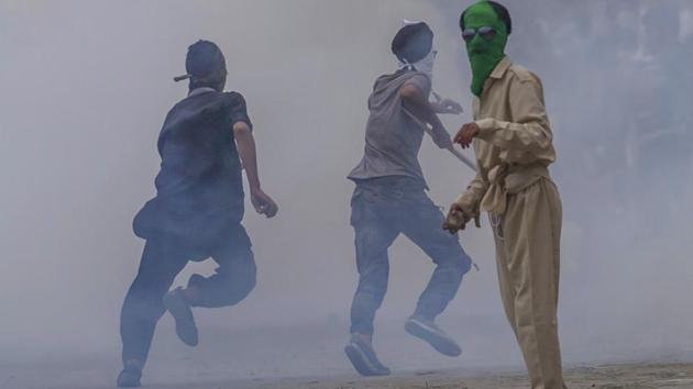 A Kashmiri protester holds a rock in his hand as others run for cover amid tear gas smoke during a protest outside Eidgha, a prayer ground, in Srinagar.(AP)