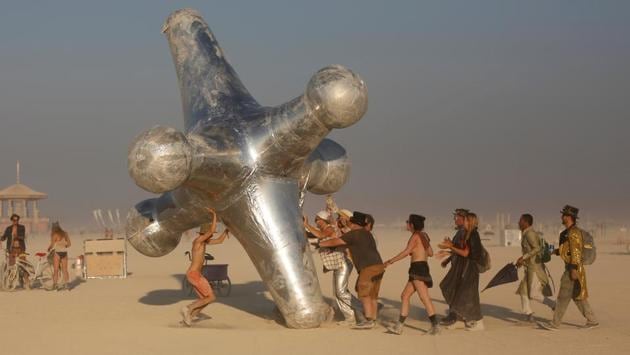 Attendees push the art piece ‘The Jack’ along Black Rock City. The festival operates on a ten principle philosophy that all revellers are expected to adhere to as members of Burning Man festivities. These include radical inclusion, gifting, decommodification, radical self-reliance, radical self-expression, communal effort, civic responsibility, leaving no trace, participation and immediacy. (Jim Urquhart / REUTERS) 