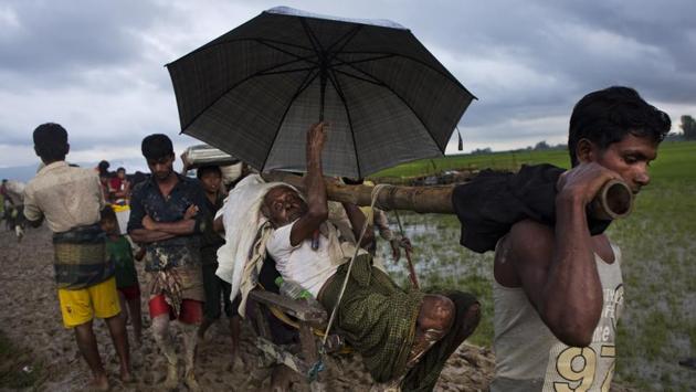 Ethnic Rohingya carry an elderly man as they walk through rice fields after crossing over to the Bangladesh side of the border near Cox's Bazar's Teknaf area on September 1, 2017. Most refugees have fled leaving behind all apart from what they could immediately carry. In most cases these have been a essentials such as food, some utensils or protective tarp or mattresses. (Bernat Armangue / AP) Ethnic Rohingya carry an elderly man as they walk through rice fields after crossing over to the Bangladesh side of the border near Cox's Bazar's Teknaf area on September 1, 2017. Most refugees have fled leaving behind all apart from what they could immediately carry. In most cases these have been a essentials such as food, some utensils or protective tarp or mattresses. (Bernat Armangue / AP)