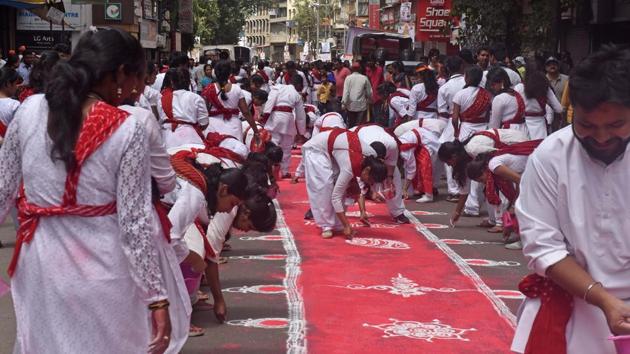 Girls and boys draw rangoli on the Laxmi road during Ganesh visarjan procession in Pune on Tuesday.  (Pratham Gokhale/HT PHOTO) 