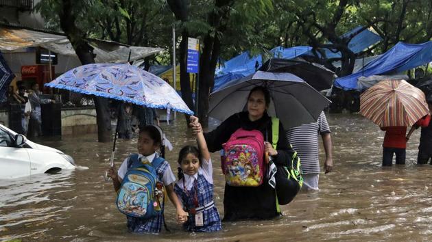 Schoolchildren wade past a waterlogged railway street in the rain in Mumbai, India, 2017(AP)