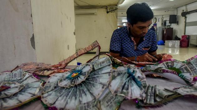DIVIDE TO RULE: A man tries to separate the currency notes in a garland. (Kunal Patil/HT Photo) 
