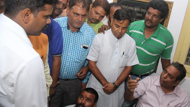 District magistrate SA Murugesan (standing left) and mayor Vinod Chamoli (sitting right) outside the DM’s office in Dehradun.(HT Photo)