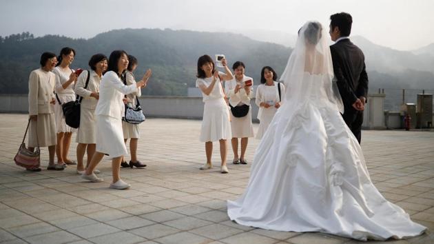 Relatives take photographs of a newlywed couple before the mass wedding ceremony. At first the ceremonies involved just a few dozen couples but numbers mushroomed over the years. In 1997, 30,000 couples tied the knot in Washington, and two years later around 21,000 filled the Olympic Stadium in Seoul. (Kim Hong-Ji / REUTERS) Relatives take photographs of a newlywed couple before the mass wedding ceremony. At first the ceremonies involved just a few dozen couples but numbers mushroomed over the years. In 1997, 30,000 couples tied the knot in Washington, and two years later around 21,000 filled the Olympic Stadium in Seoul. (Kim Hong-Ji / REUTERS)