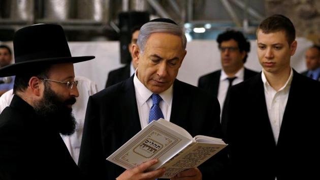 Israel’s Prime Minister Benjamin Netanyahu (Centre) reads a prayer with Western Wall Rabbi Shmuel Rabinowitz as his son Yair (right) stands next to him, at the Western Wall, in Jerusalem’s Old City in March.(Reuters File Photo)