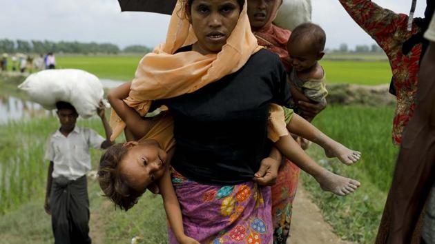 A Rohingya Muslim refugee carries a child as they arrive from Myanmar through Lomba Beel after crossing the Naf river, in the Bangladeshi town of Teknaf on September 7, 2017. (K M Asad / AFP) A Rohingya Muslim refugee carries a child as they arrive from Myanmar through Lomba Beel after crossing the Naf river, in the Bangladeshi town of Teknaf on September 7, 2017. (K M Asad / AFP)