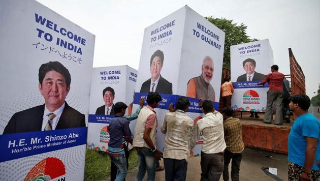 Workers carry a hoarding featuring Prime Minister Narendra Modi and his Japanese counterpart Shinzo Abe ahead of Abe's visit in Ahmedabad.(REUTERS)