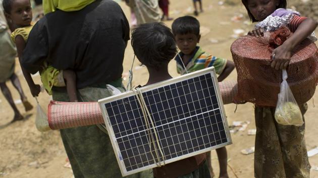A Rohingya Muslim child carries a solar panel as she crosses over the border from Myanmar into Bangladesh in Teknaf area. Small solar panels are everywhere in the makeshift refugee camp that has sprouted up to accommodate many of the more than 270,000 people the UN says have entered Bangladesh since the violence started. The dark-blue-and-white panels are also perched on the plastic roofs of their shelters. ‘We got it so that in the dark we can have some light,’ said one man. (Bernat Armangue / AP) A Rohingya Muslim child carries a solar panel as she crosses over the border from Myanmar into Bangladesh in Teknaf area. Small solar panels are everywhere in the makeshift refugee camp that has sprouted up to accommodate many of the more than 270,000 people the UN says have entered Bangladesh since the violence started. The dark-blue-and-white panels are also perched on the plastic roofs of their shelters. ‘We got it so that in the dark we can have some light,’ said one man. (Bernat Armangue / AP)