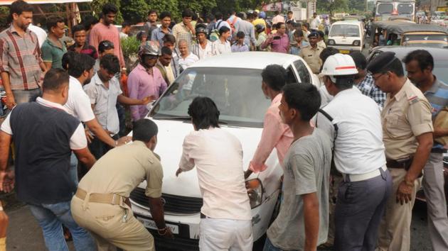 Locals trying to remove the car from the road as the driver fled leaving the vehicle abandoned on seeing police check at RD Tata Square in Jamshedpur on Monday. (Manoj Kumar/HT photo) Locals trying to remove the car from the road as the driver fled leaving the vehicle abandoned on seeing police check at RD Tata Square in Jamshedpur on Monday. (Manoj Kumar/HT photo)