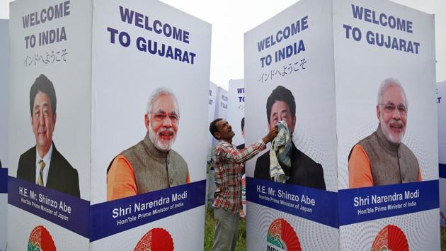A worker cleans a hoarding featuring India's Prime Minister Narendra Modi and his Japanese counterpart Shinzo Abe ahead of Abe's visit, in Ahmedabad, September 10.(Reuters Photo)