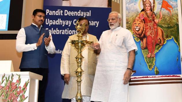 Prime Minister Narendra Modi lights the lamp as minister of state for culture and environment Mahesh Sharma and sports minister Rajyavardhan Singh Rathore look on, during a function on the occasion of 125th anniversary of Vivekananda’s Chicago Address and birth centenary of Deendayal Upadhyay in New Delhi on Monday.(Sushil Kumar/HT Photo)