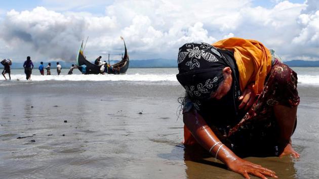 An exhausted Rohingya refugee woman touches the shore after crossing the Bangladesh-Myanmar border by boat through the Bay of Bengal, in Shah Porir Dwip, Bangladesh, on Monday.(Reuters Photo)