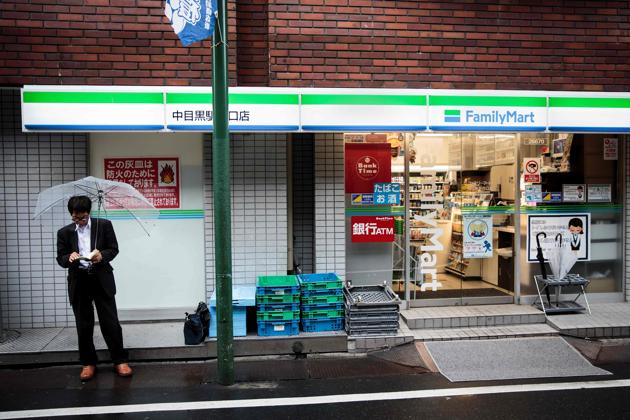 A man reads a book as he smokes next to a convenience store in the Nakameguro district in Tokyo.(AFP/Behrouz Mehri)