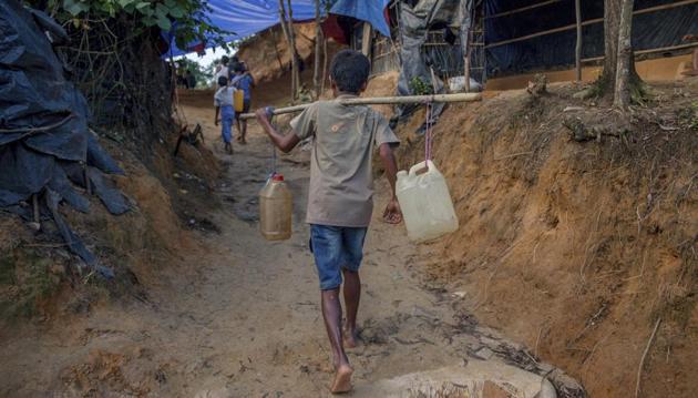 A Rohingya Muslim boy, who crossed over from Myanmar into Bangladesh, carries jerry cans filled with water collected from a nearby hand pump at Balukhali refugee camp, Bangladesh, on Wednesday.(AP)