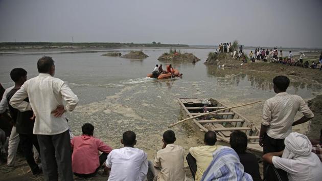 Rescuers search in the Yamuna River as villagers gather after a country boat capsized near Baghpat town in Uttar Pradesh. (AP Photo) Rescuers search in the Yamuna River as villagers gather after a country boat capsized near Baghpat town in Uttar Pradesh. (AP Photo)