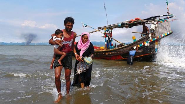 Smoke is seen on Myanmar's side of border as Rohingya refugees get off from a boat after crossing the Bangladesh-Myanmar border through the Bay of Bengal in Shah Porir Dwip, Bangladesh.(REUTERS) Smoke is seen on Myanmar's side of border as Rohingya refugees get off from a boat after crossing the Bangladesh-Myanmar border through the Bay of Bengal in Shah Porir Dwip, Bangladesh.(REUTERS)