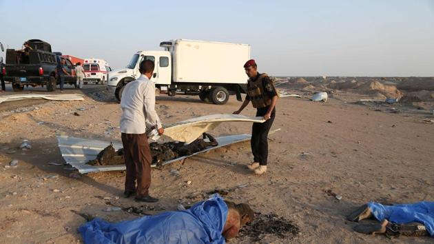 Graphic content / A member of the Iraqi security forces and a civilian cover the bodies of victims of an attack after gunmen and suicide car bombers killed dozens of people in an assault claimed by Islamic State (IS) group jihadists near the southern Iraqi city of Nasiriyah on September 14, 2017. (AFP) Graphic content / A member of the Iraqi security forces and a civilian cover the bodies of victims of an attack after gunmen and suicide car bombers killed dozens of people in an assault claimed by Islamic State (IS) group jihadists near the southern Iraqi city of Nasiriyah on September 14, 2017. (AFP)
