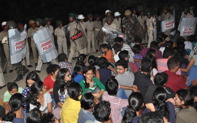 Policemen watch as students of the National University of Study and Research in Law stage a dharna against the alleged misappropriation of funds in front of university gate at Kanke in Ranchi.(Hindustan Times)