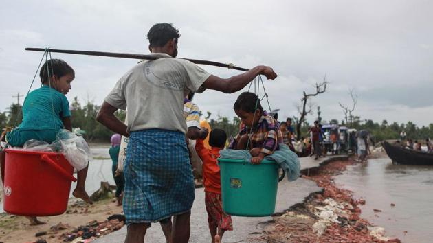 A Rohingya refugee carries two children in buckets as they arrive in Bangladesh at Shah Porir Dwip in Teknaf on September 9, 2017, as they flee violence in neighbouring Myanmar.(AFP) A Rohingya refugee carries two children in buckets as they arrive in Bangladesh at Shah Porir Dwip in Teknaf on September 9, 2017, as they flee violence in neighbouring Myanmar.(AFP)