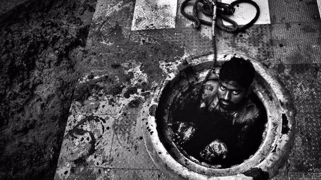 25-year-old Vikas, strips down and lowers himself into a sewer full of silt. Soon he is up to his chest in black muck. He fills a pail with the silt, which his co-workers pull out with the help of the rope attached to it, and empty it, before sending it back to him. The stench is overpowering, even for someone standing near. (Ravi Choudhary / HT Photo)