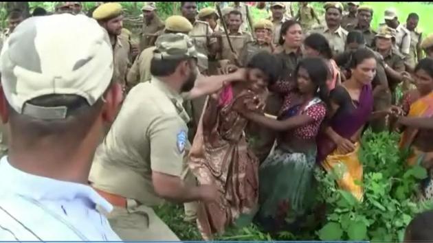 A policeman attached to the Telangana forest department restrains a tribal woman in Jalagalancha.(HT Photo)