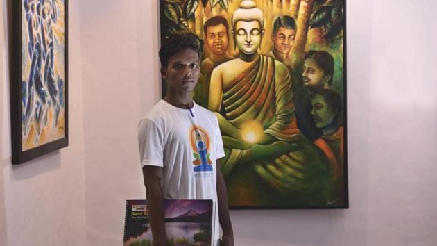 Ramesh, an inmate poses for a photo in front of his art work on display at a gallery at the Tihar School Of Art in New Delhi. The paintings are in different mediums—oil, acrylic, water paint—dealing with myriad themes of streetscapes, metro trains, portraits of women, the ghats of Banaras among many others. (Vipin Kumar / HT Photo) 