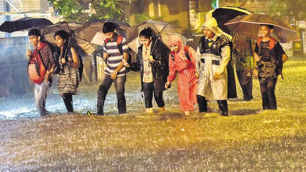 People walk through water logged street during heavy rain at Sion in Mumbai on Tuesday.(HT PHOTO)